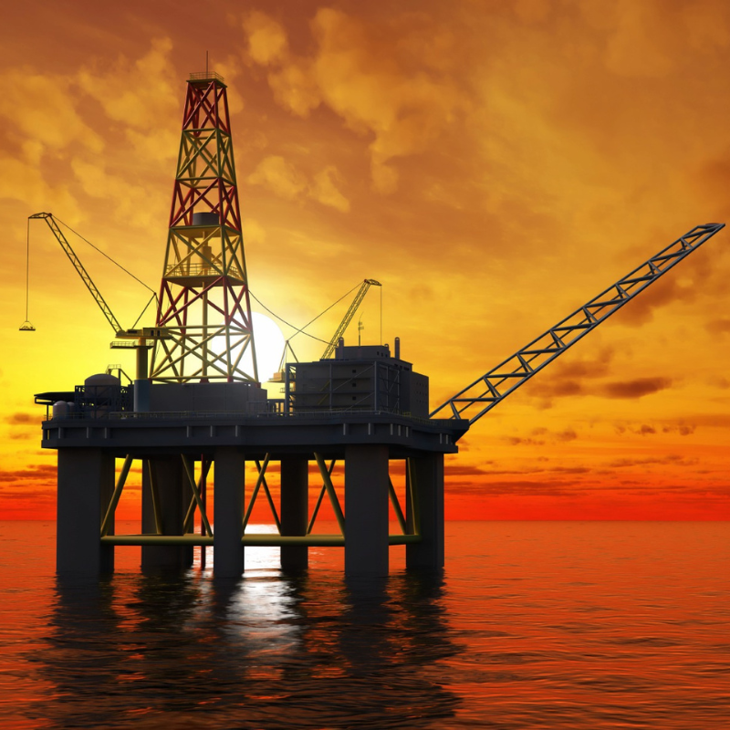 An off shore oil rig with the sun setting in the background